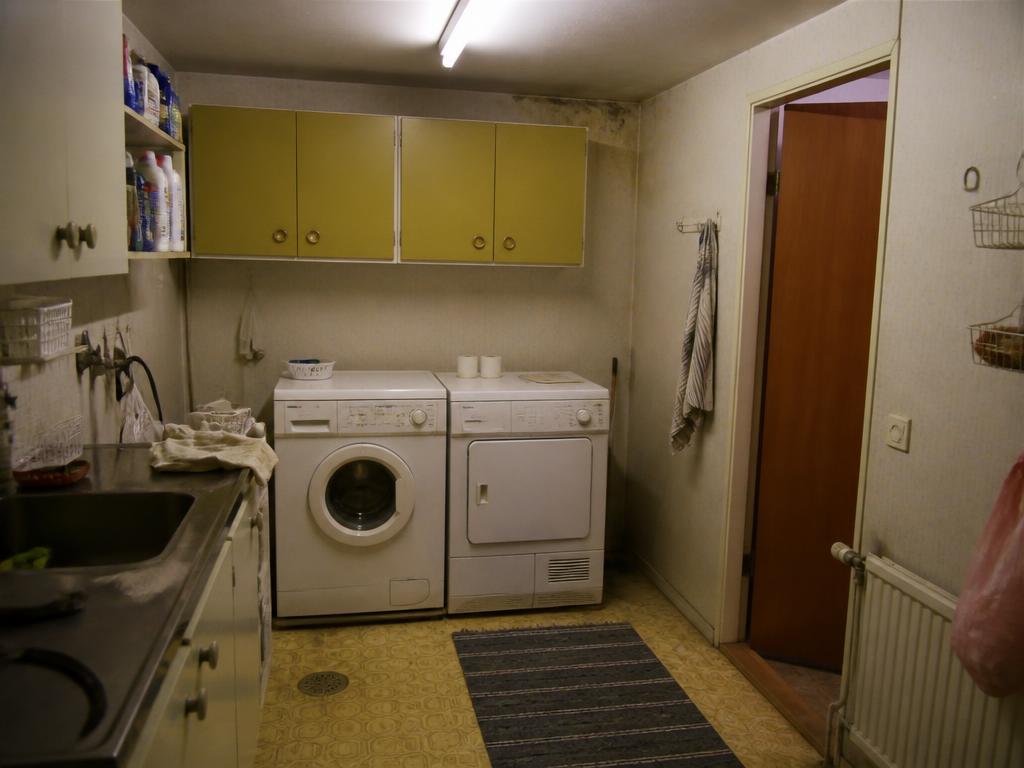 Sliten tvättstuga före renovering med gamla skåp och slitna ytor
